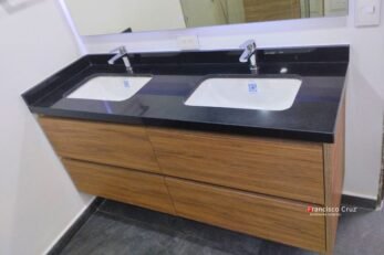 Primer plano de dos cajones de mueble de baño abiertos, mostrando el mecanismo de guías de cierre lento certificado de la marca Blum (o DTC/Häfele). Se resalta la suavidad y el espacio de almacenamiento optimizado.