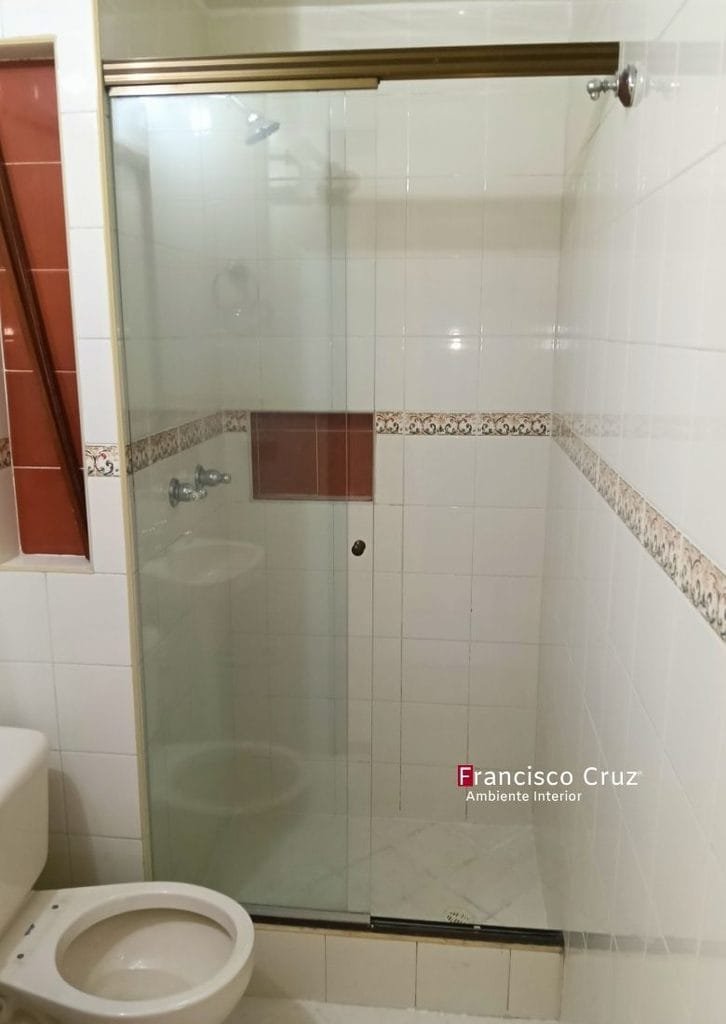 Cabina de ducha con división en vidrio, perfilería metálica y cerámicas con cenefa decorativa.