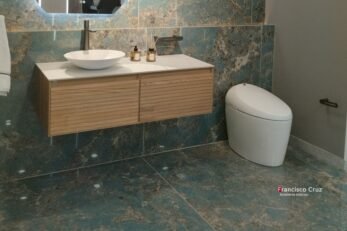 Mueble de baño suspendido en madera con lavamanos sobre mesón, sanitario contemporáneo de línea baja y porcelanato de gran formato en diseño de baño accesible