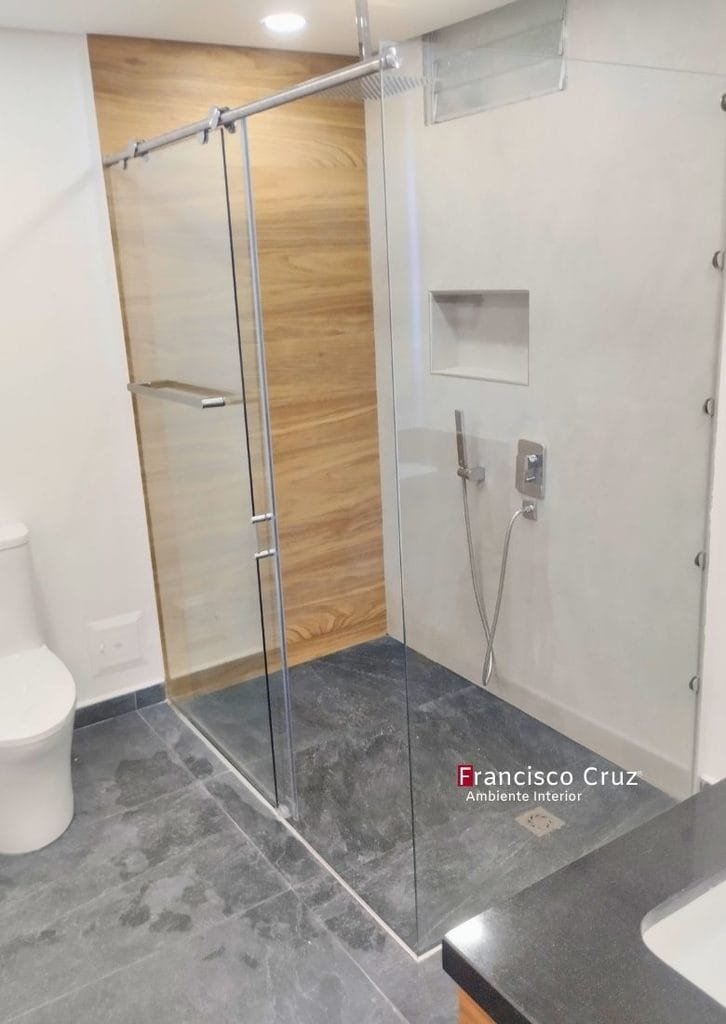 Ducha con división de vidrio templado, muro de acento tipo madera, piso oscuro y nicho de almacenamiento.