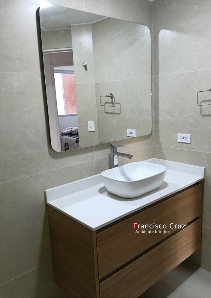 Mueble flotante de madera con dos cajones, mesón blanco, lavamanos de sobreponer y espejo rectangular de bordes redondeados.