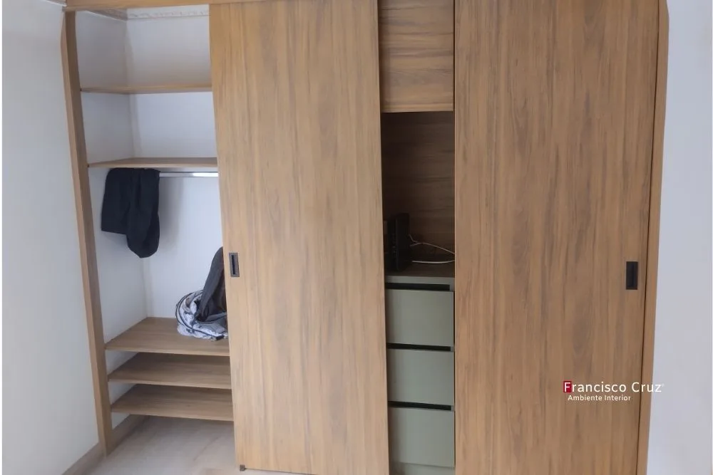 Closet moderno en melamínico nogal con puertas corredizas y gavetas en verde sage. Francisco Cruz Interiores Bogotá